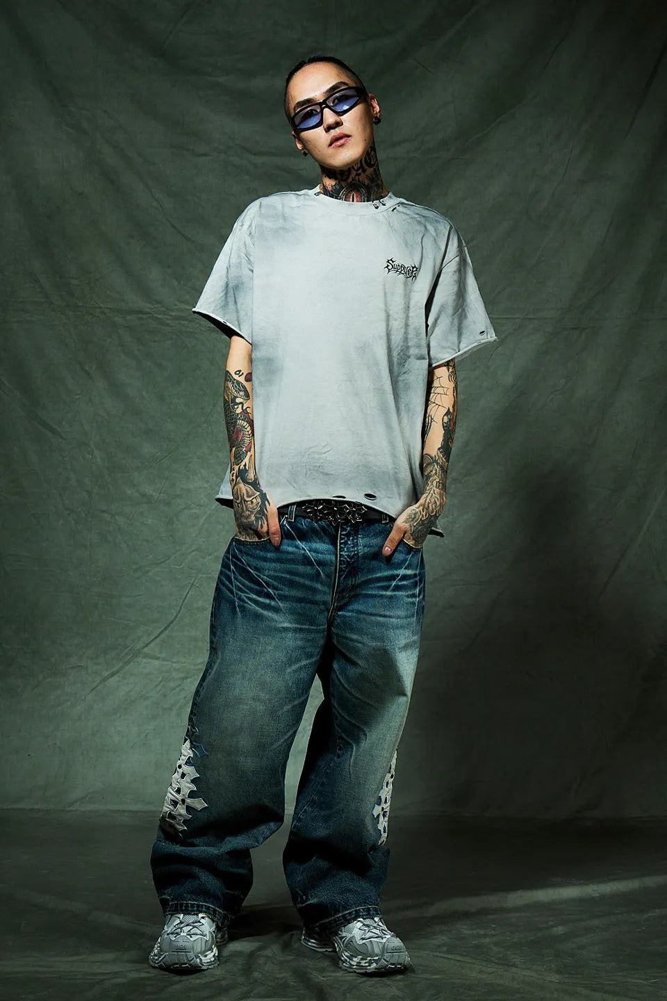SUPPLIER Pierced Tribal Bones Tee - GRAY の着用画像。ボックスシルエットを生かしたベルト見せのコーデ。パンツはクロスパッチ付きのデニム。