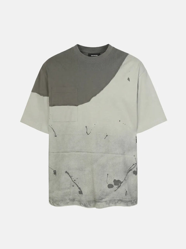 DistopionのFacade Splatter Tee。ウォッシュ加工が施されたライトグレー系のボディに、ダークトーンの切りっぱなしアシンメトリー胸パネルと同系色ポケット、全体に飛び散るような黒のインクスプラッターグラフィックがあしらわれた超厚手オーバーサイズTシャツ。
