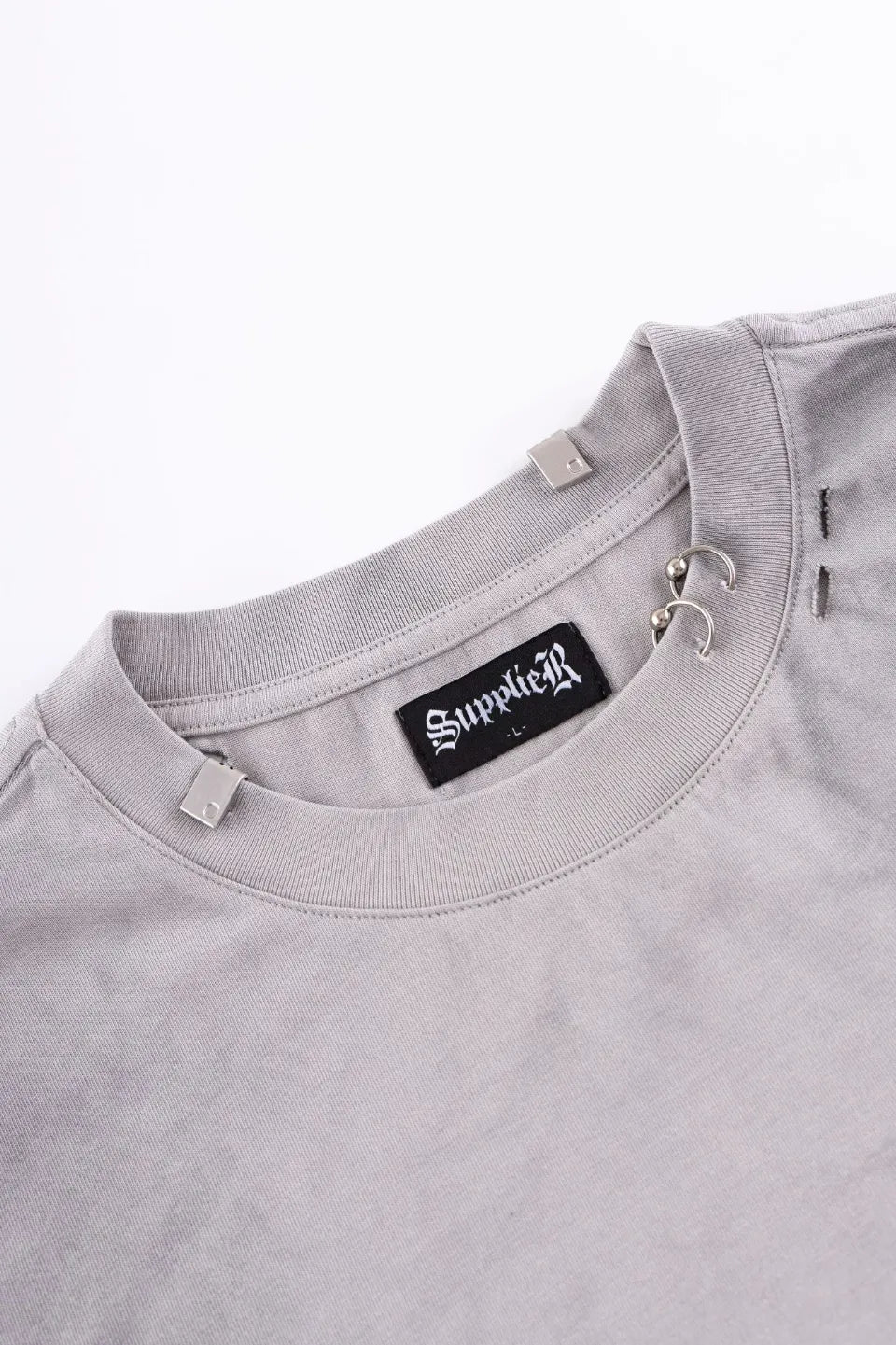 Pierced Tribal Bones Tee - gray襟元のアップ。シルバーのリングピアスパーツとブランドプレート、首回りのクラッシュ加工のディテール。