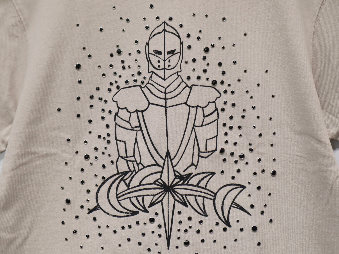 LUMINOUS DAWN SKETCH KNIGHT TEE - BEIGEのプリントとパール部分のアップ。