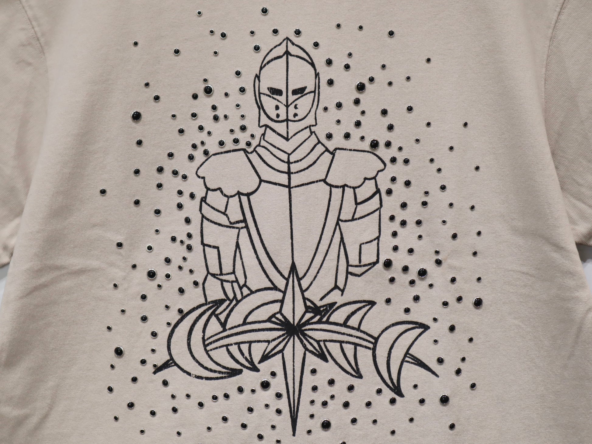 LUMINOUS DAWN SKETCH KNIGHT TEE - BEIGEのプリントとパール部分のアップ。