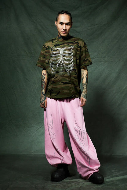 SUPPLIER Rhinestone Fire Bone Tee - KAHKIの着用画像。ピンクのスエットバギーパンツとブラックのブーツを組み合わせたコーデ。