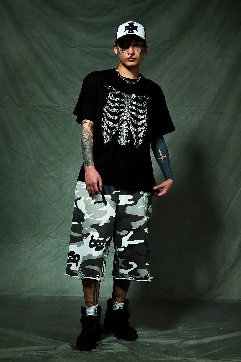 SUPPLIER Rhinestone Fire Bone Tee - BLACKの着用画像。クロスモチーフのメッシュキャップと白黒迷彩柄のジョーツを組み合わせたモノトーンコーデ。