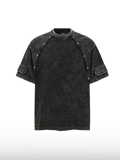 DistopionのShatter Point Rivet Tee。アシッドウォッシュ加工による独特のムラ感がある黒のオーバーサイズTシャツ。首元から両肩にかけて配置された金属製スナップボタンと、両袖のカーゴポケットが特徴的なフロントビュー。