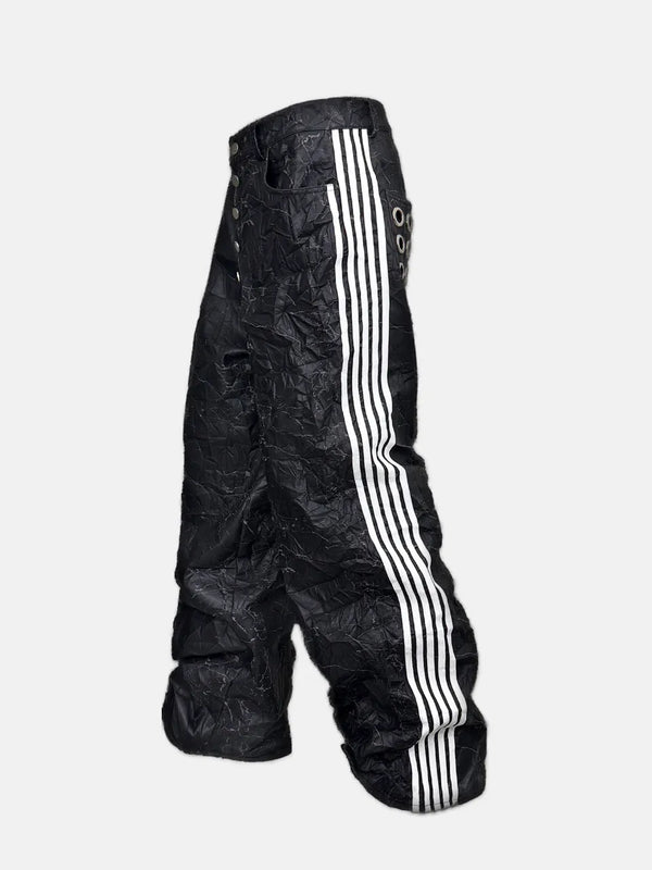 DistopionのVillain Pantsのサイドビュー。黒いシワ加工のボディの側面に走る、クラシックなアスレチックスタイルの白い4本線（サイドストライプ）と、足元に大胆にボリュームが溜まるオーバーサイズなシルエットの美しさ。