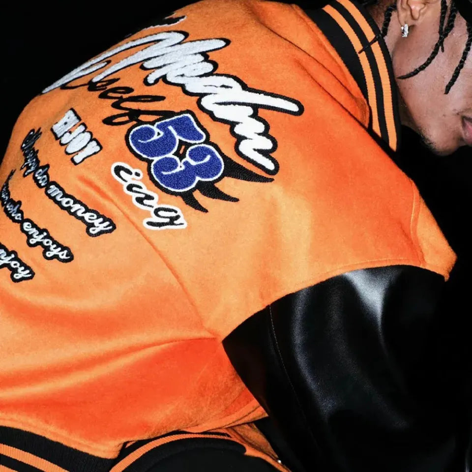 【MR. ENJOY DA MONEY】 BASIC EMBROIDERED BASEBALL JERSEY（ORANGE） バックグラフィック刺繍が見えるルック画像。