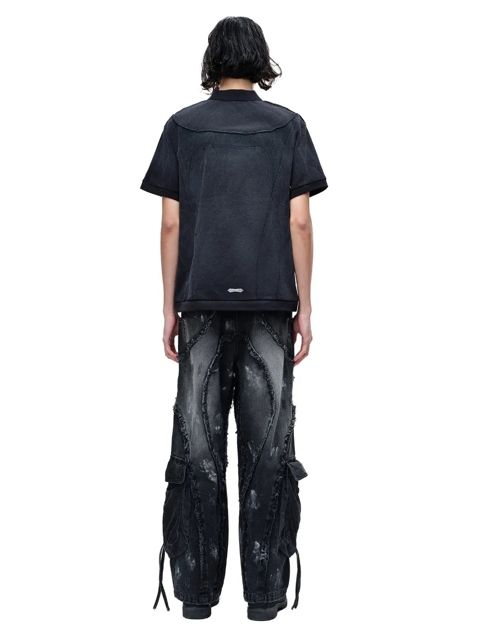 【THE BOY HAS NO PATIENCE】 LUMINOUS DAWN STRUCTURED POLO （ブラック） 変形切替デザインが特徴的なポロシャツとワイドパンツを着用したモデルの全身背面画像