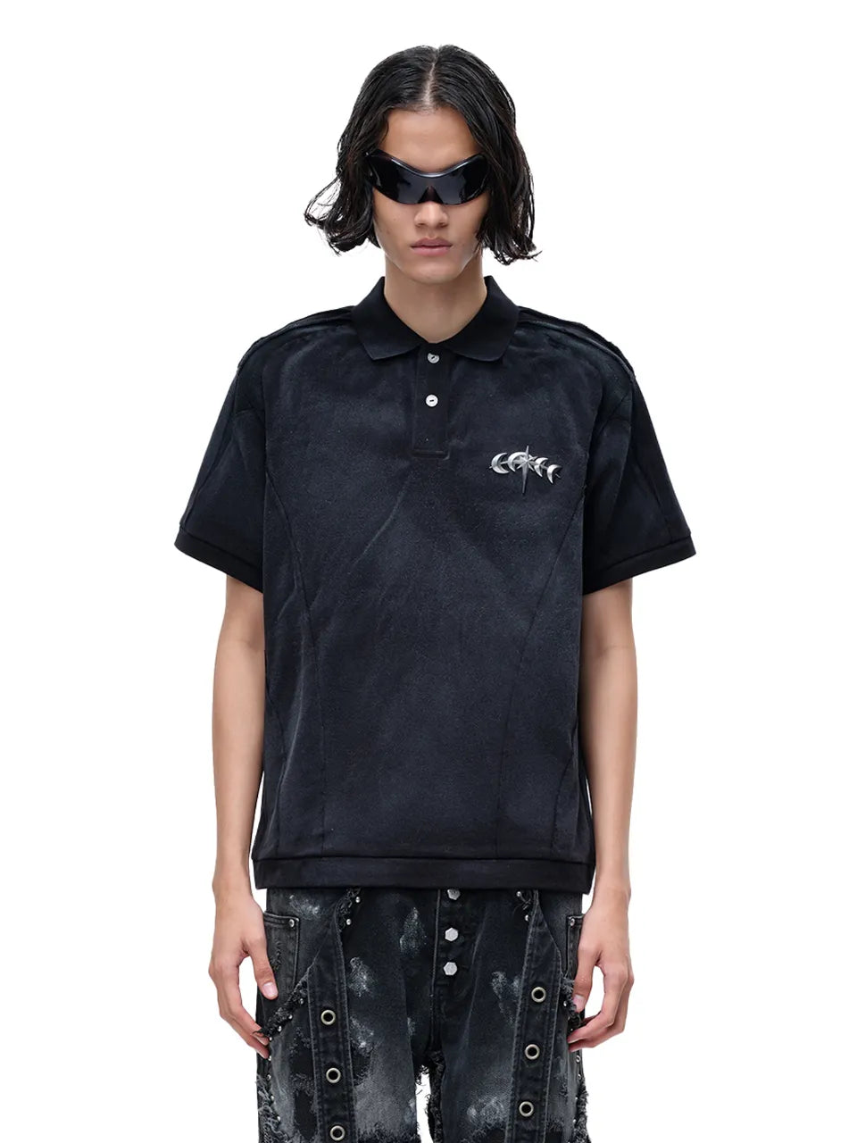 【THE BOY HAS NO PATIENCE】 LUMINOUS DAWN STRUCTURED POLO （ブラック） 胸元にメタルロゴをあしらったポロシャツを着用したモデルのバストアップ正面画像
