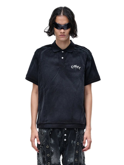 【THE BOY HAS NO PATIENCE】 LUMINOUS DAWN STRUCTURED POLO （ブラック） 胸元にメタルロゴをあしらったポロシャツを着用したモデルのバストアップ正面画像