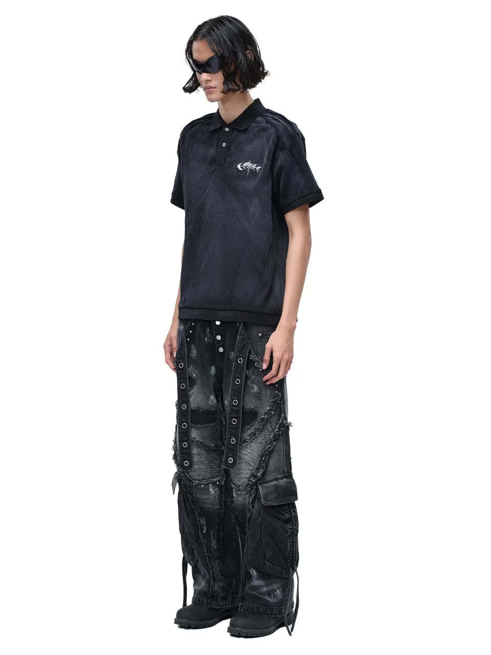 【THE BOY HAS NO PATIENCE】 LUMINOUS DAWN STRUCTURED POLO （ブラック） 胸元にメタルロゴが入ったポロシャツとワイドパンツを着用したモデルの全身斜め画像